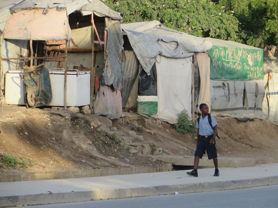 boy walking past dilapidated shelters in Haiti