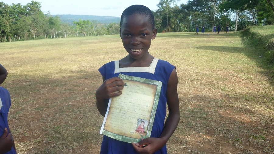 Ugandan girl from Catholic child sponsorship program holding letter