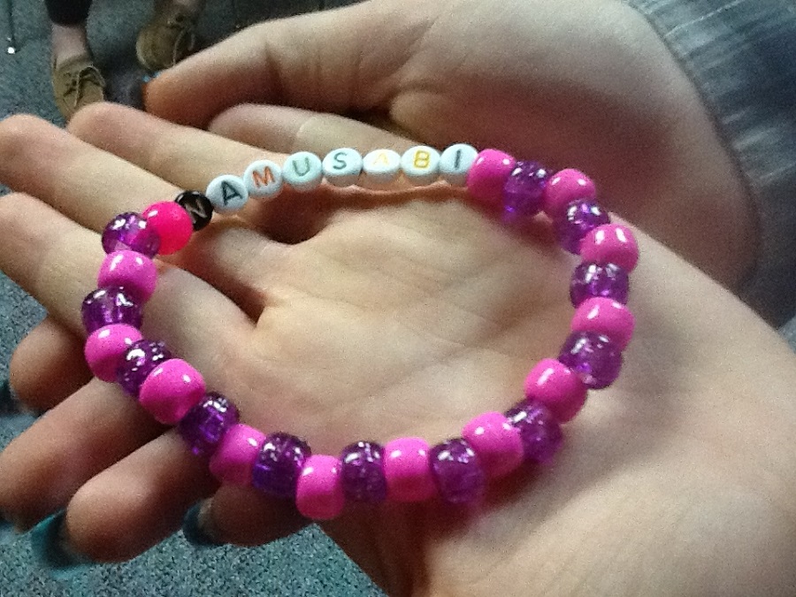 an image of a bracelet with name inscribed held in the hands of a girl