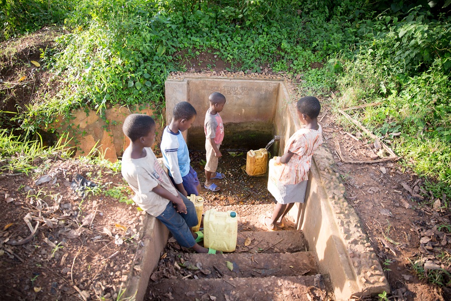 children filling jerry cans with water from public pipe