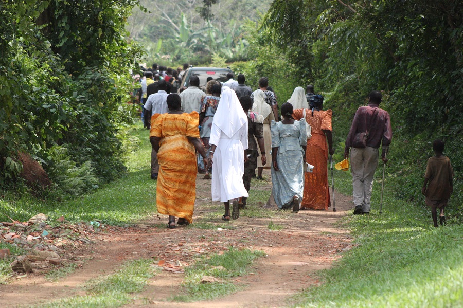 The mourners walk to the graveyard to witness the burial the late sister.