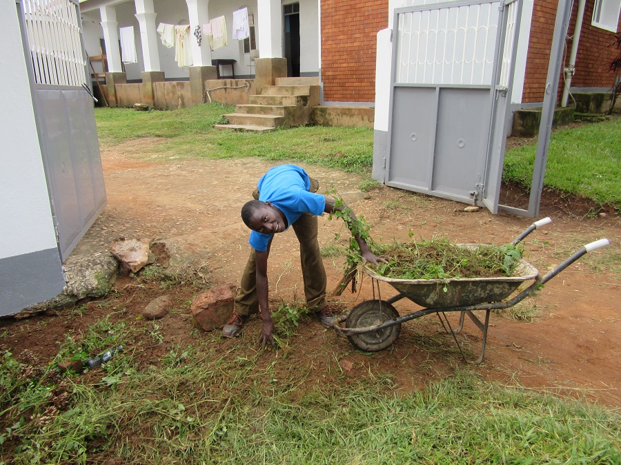 Male teen bent next to wheel barrow.